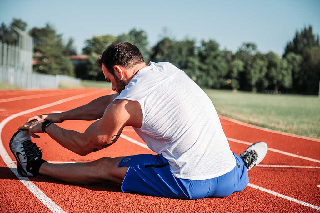 Man stretching on running track